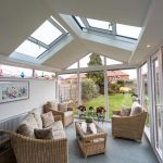 A conservatory with a glass roof and wicker furniture providing Conservatory Extensions in Bishop's Cleeve.